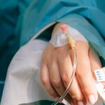 Ręka chorej osoby na łóżku szpitalnym