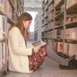 Młoda dziewczyna czytająca książki w bibliotece na studiach