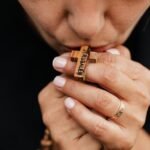 Kobieta całująca drewniany krzyżyk od różańca