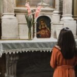 Kobieta modląca się przed obrazem Matki Bożej w kościele