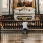 Mężczyzna modlący się na kolach przed ołtarzem w kościele