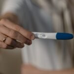 Kobieta trzymająca w ręku test ciążowy z pozytywnym wynikiem