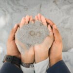 Ręce małżeństwa trzymające obrączki na piasku