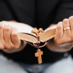 Modląca się kobieta trzymająca w rękach biblię i różaniec