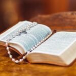 Różowy różaniec leżący na otwartej biblii
