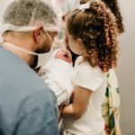 Ojciec i córki trzymające na rękach małe dziecko, brata