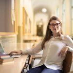 Uśmiechnięta dziewczyna siedząca z laptopem na studiach