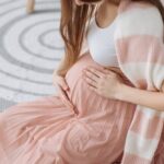 Kobieta w ciąży trzymająca się za brzuch