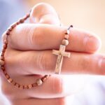 Mały drewniany różaniec trzymany w dłoni