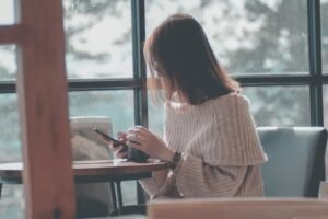 Dziewczyna siedząca przy stole, trzymająca w rękach telefon