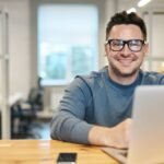 Radosny mężczyzna w pracy przed komputerem