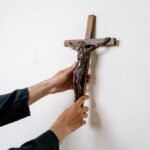 Ręce zawieszające drewniany krzyż na ścianie
