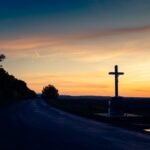 Krzyż i droga na tle zachodzącego słońca