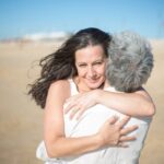 Córka przytulająca mamę na plaży