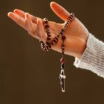 Ręka skierowana ku górze opleciona różańcem do modlitwy