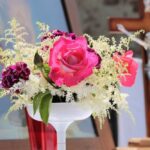 Bukiet kwiatów a w tle krzyż z Panem Jezusem