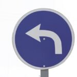 Niebieski drogowskaz z białą strzałką w lewo