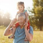 Tata, dziadek trzymający wnuczkę, dziecko na ramionach