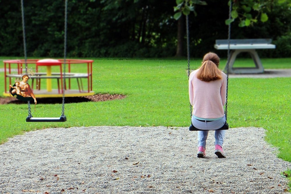 Smutna kobieta na huśtawce na placu zabaw dla dzieci