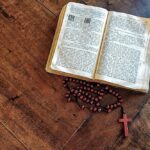 Drewniany różaniec i otwarta biblia leżące na stole
