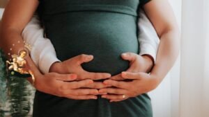 Kobieta w ciąży i ręce mężczyzny trzymające brzuch
